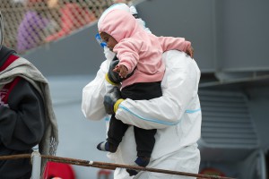 Un operatore umanitario accoglie una bambina immigrata appena sbarcata sulle coste della Sicilia